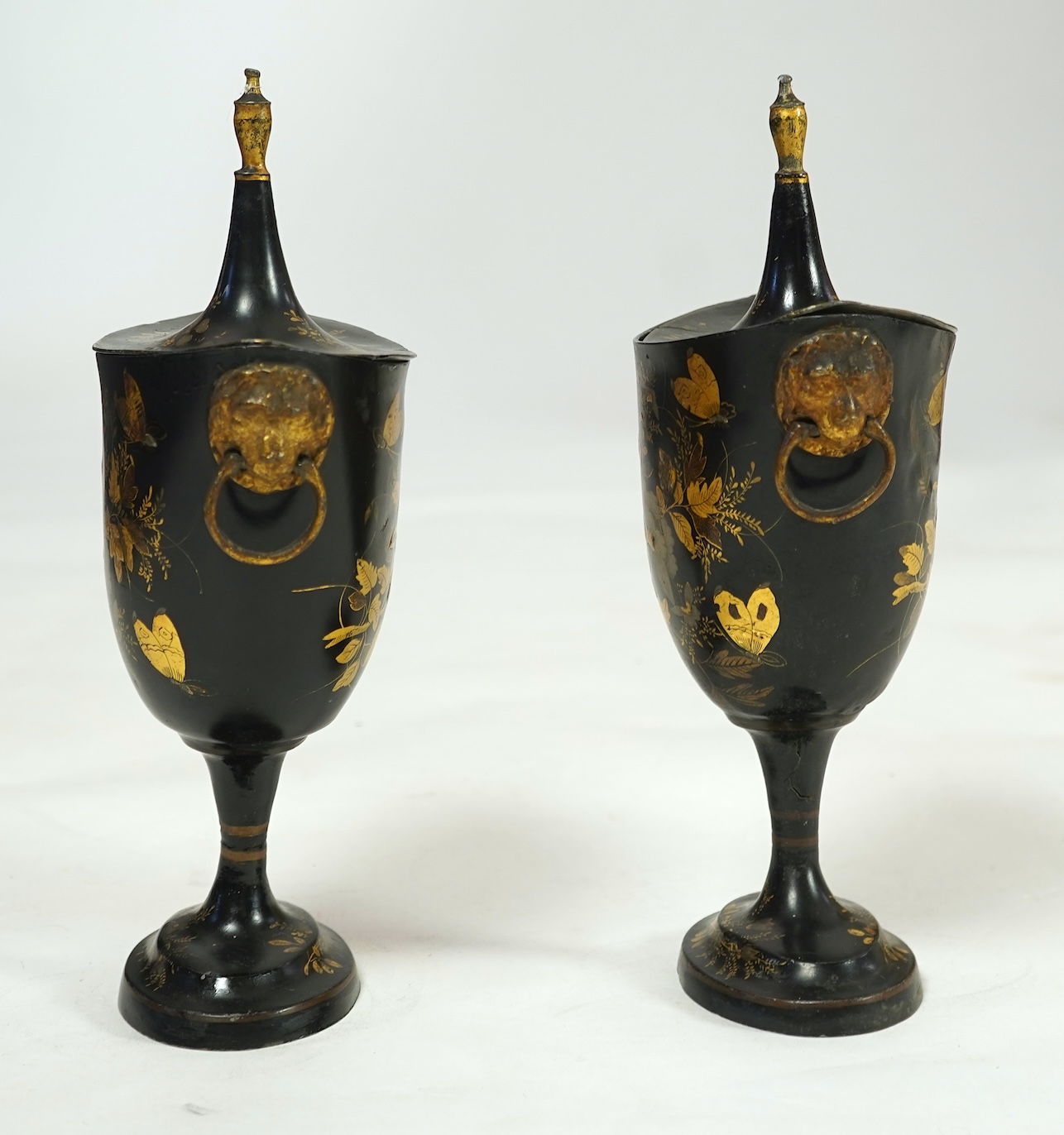 A pair of early 19th century Dutch japanned pewter chest urns and covers, and a tole ware cheese coaster